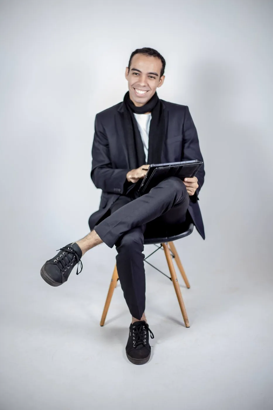 Yan Machado sentado com um tablet, sorrindo